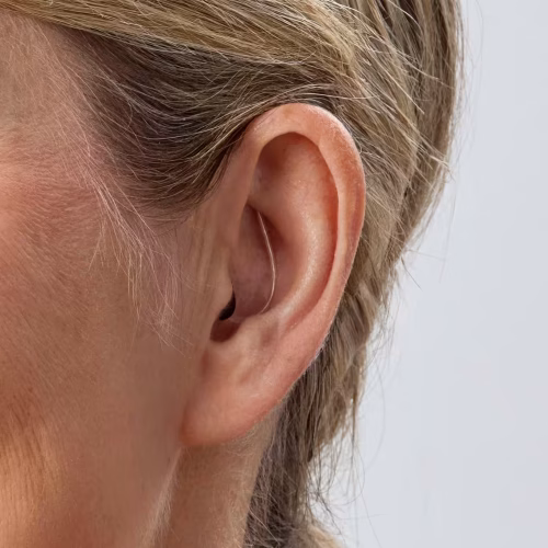 Mujer utilizando un audífono Oticon Zeal en el oído