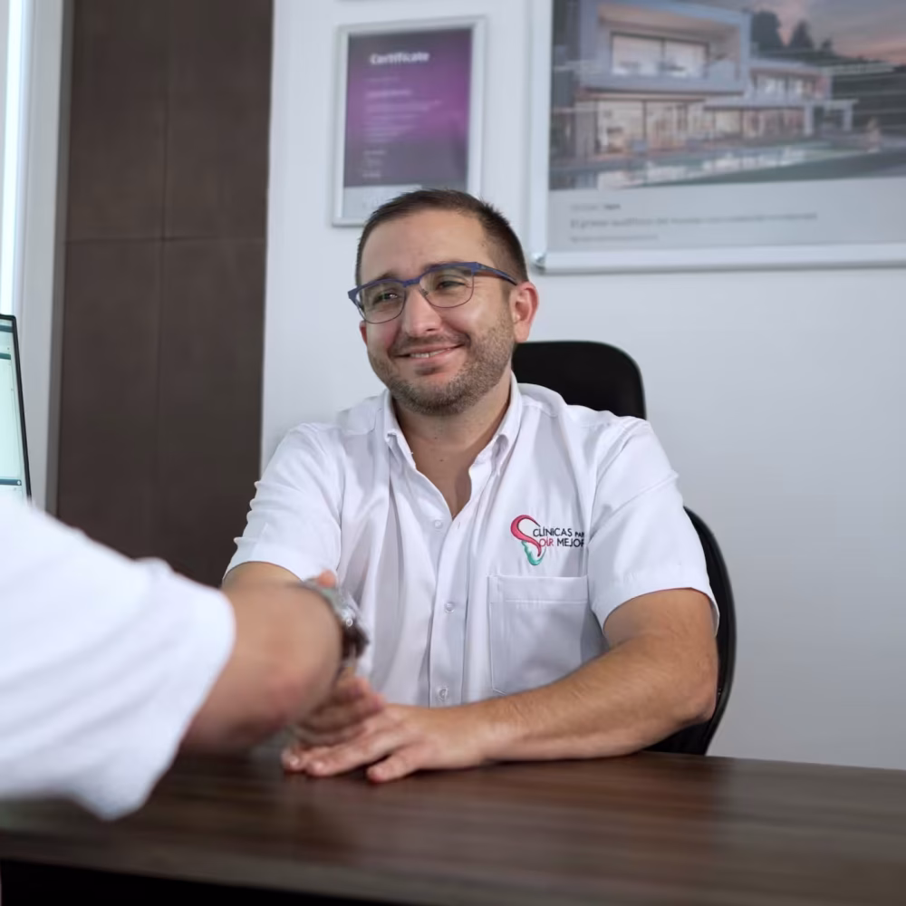 Profesional de Clínicas Para Oír Mejor saludando y acompañando a un paciente